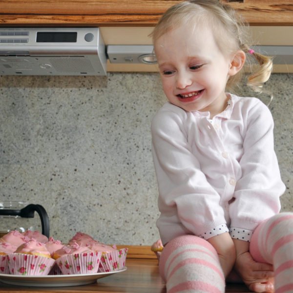 Ein Mädchen lächelt Muffins an