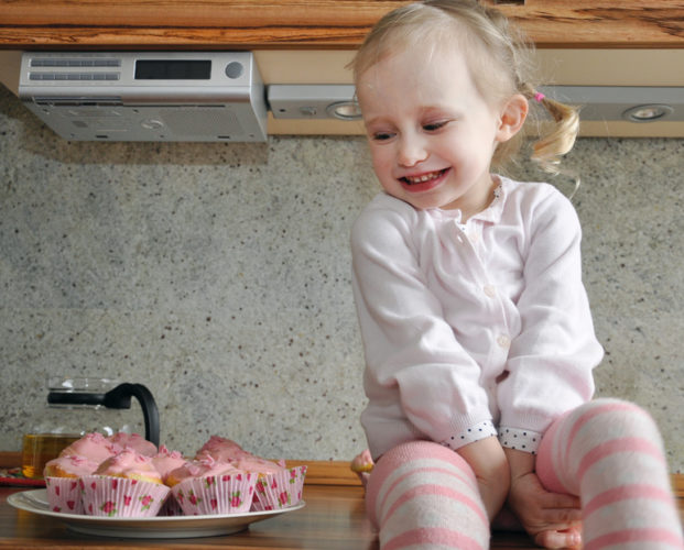 Ein Mädchen lächelt Muffins an