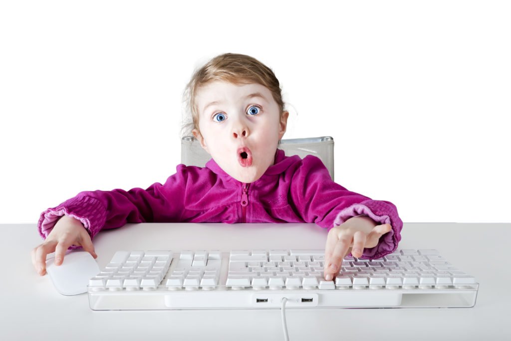 Ein Mädchen drückt auf eine Tastatur und schaut überrascht