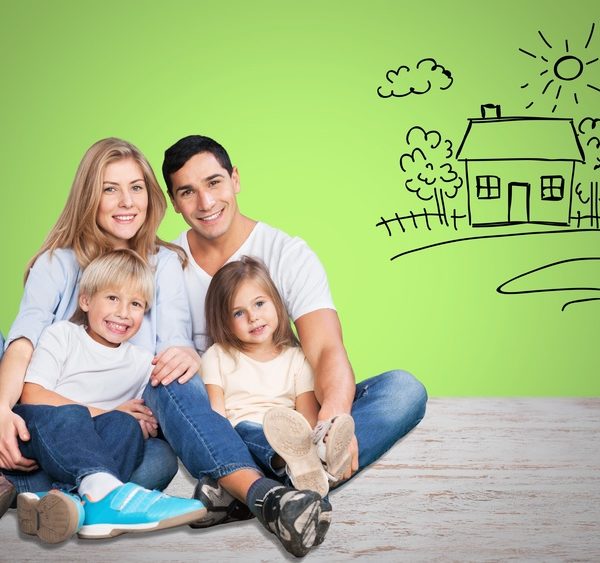 eine Familie die lächelnd zusammen sitzt und neben der ein Haus gezeichnet ist
